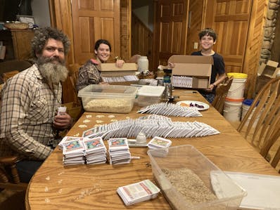 Nathan and two of his children package seeds together